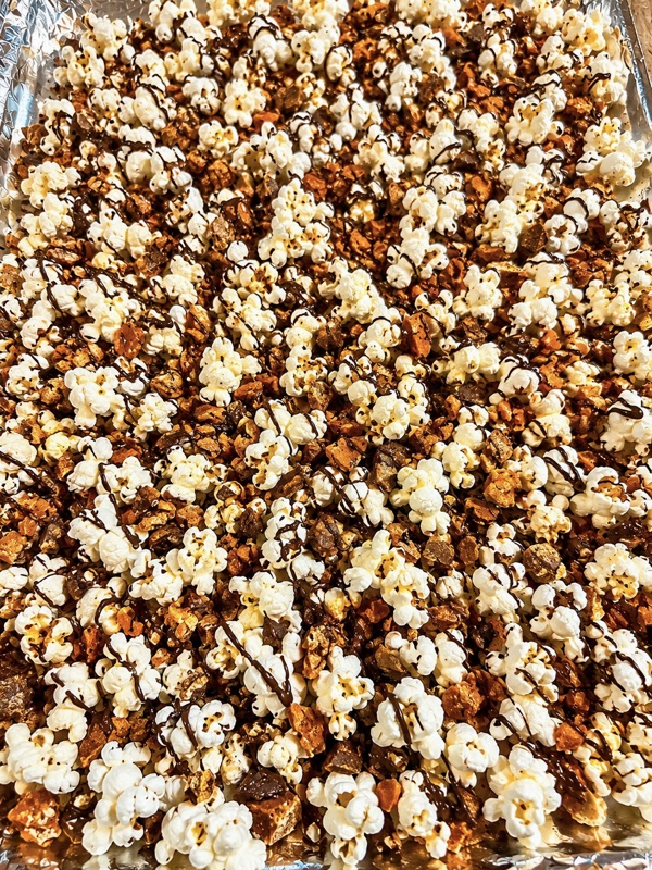 A tray of popcorn covered in chocolate drizzle and golden candy crumble
